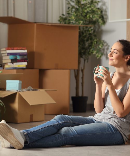 Happy tenant moving home resting breathing fresh air sitting on the floor in the night